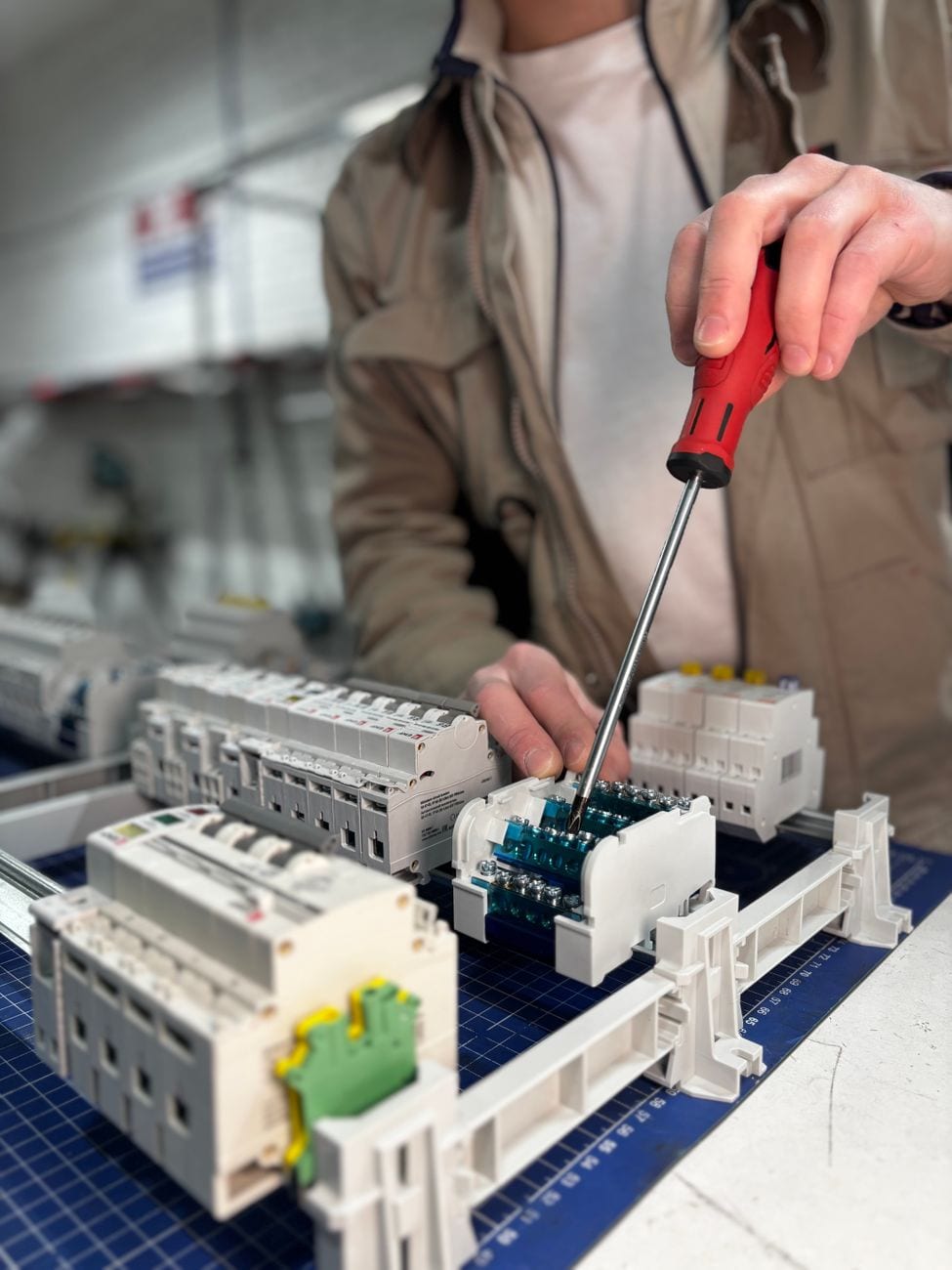 Electrician working on breaker panel components with a screwdriver